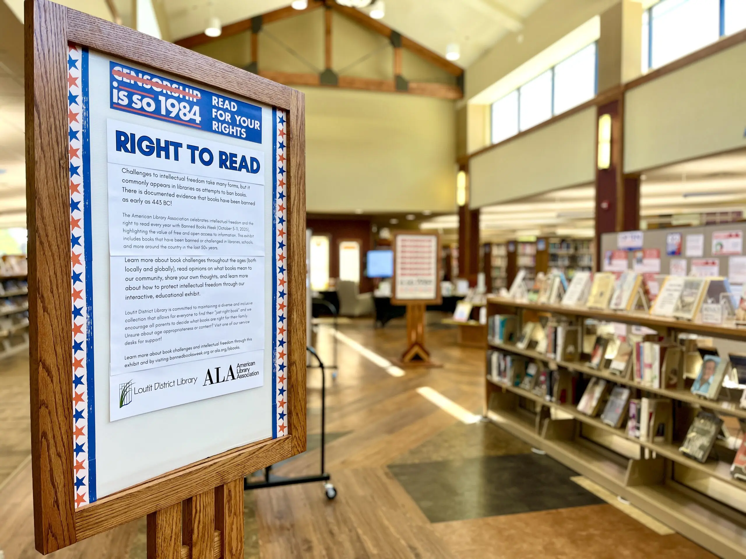 Photo of interior of a brightly lit atrium focused on a sign that says "Censorship is so 1984 Right to Read"