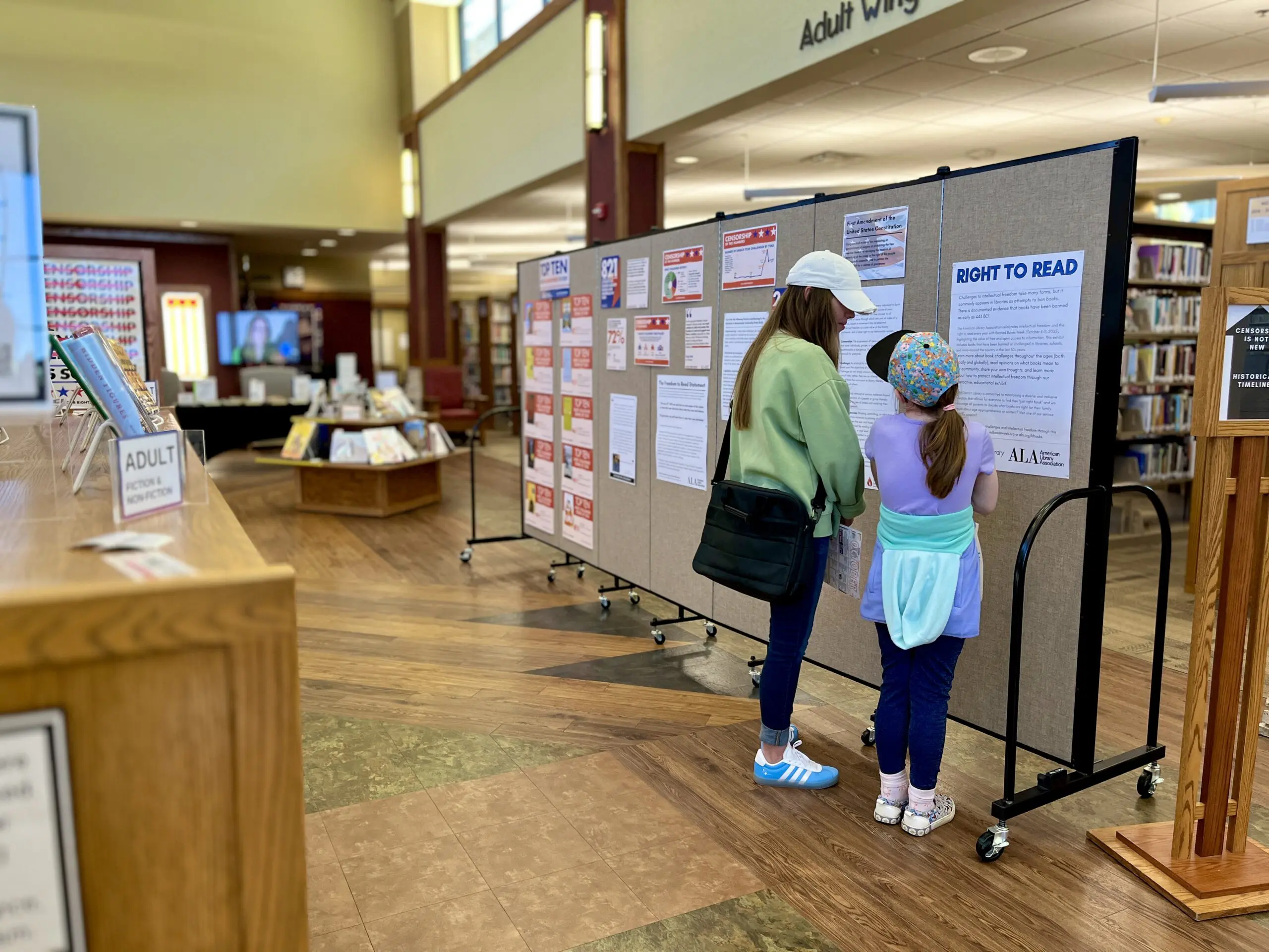 A photo of a young woman and young girl reading an exhibit about book bans and censorship